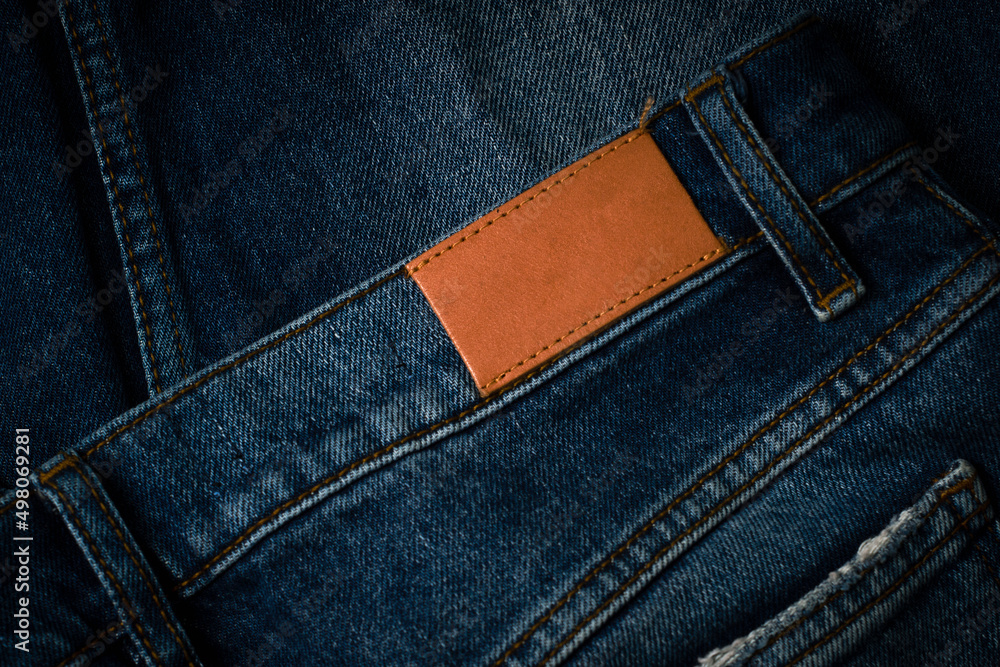Blank brown leather label sewed on a blue denim jeans. Mock up jeans tag