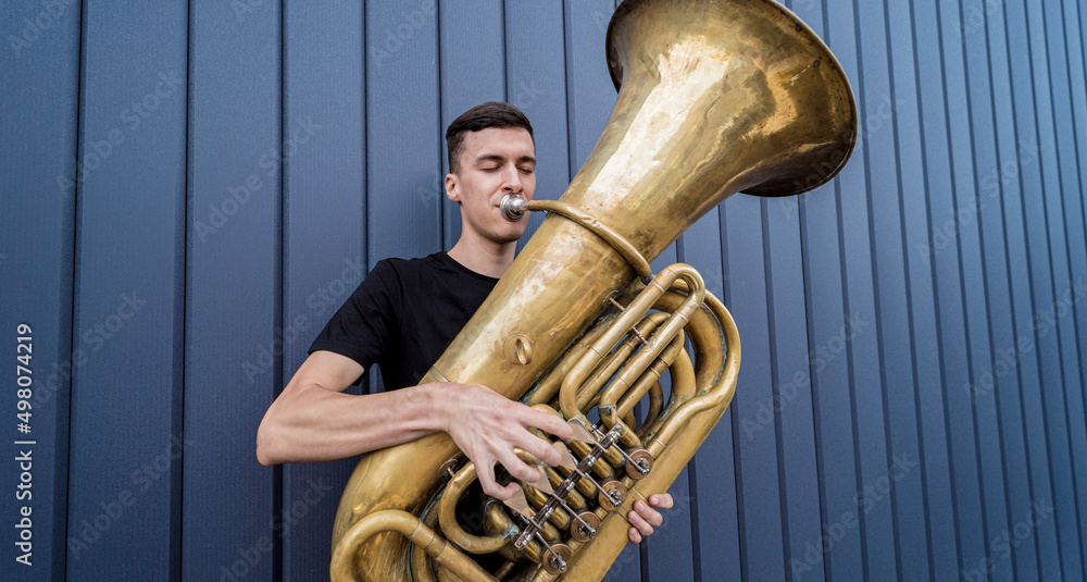 Young street musician playing the tuba near the big blue wall Stock-Foto |  Adobe Stock