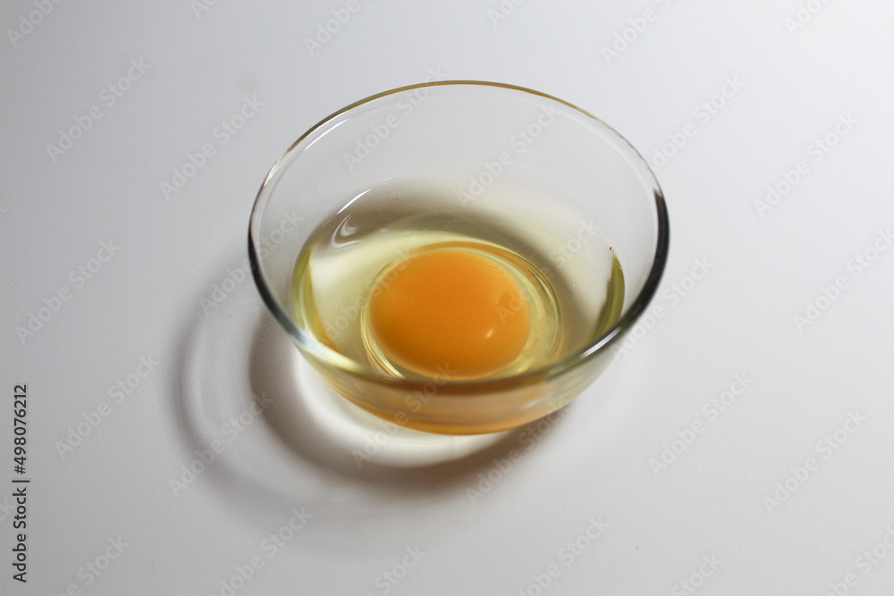 Raw egg in a glass bowl. Isolated on white background. Raw egg in a glass bowl. Isolated on white background.