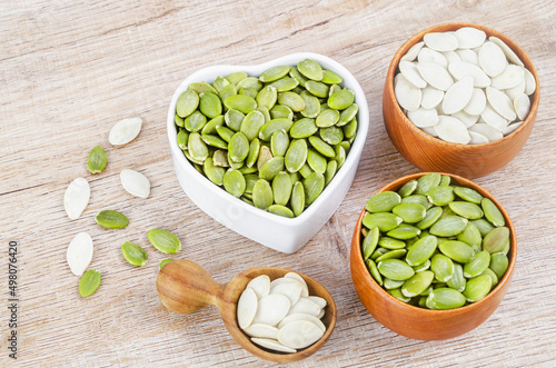 Pumpkin seeds green and unpeeled in wooden bowl.