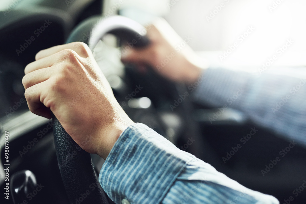 Hands at the ten and two oclock position. Closeup shot of a man driving a car.