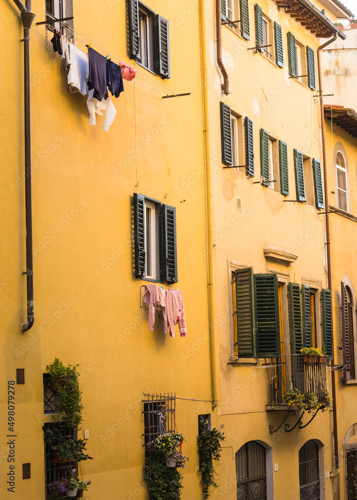 facade of yellow apartment building in Florence, Italy with clothes drying outside 