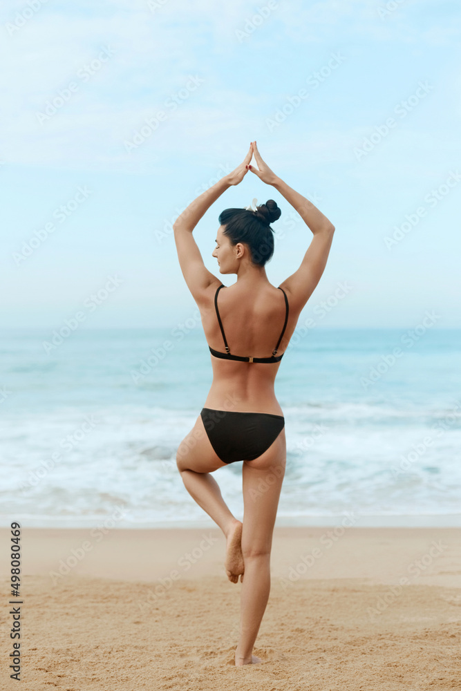 Beautiful woman doing yoga on the beach. Girl practices yoga and meditates.  Active lifestyle. Healthy and yoga concept.