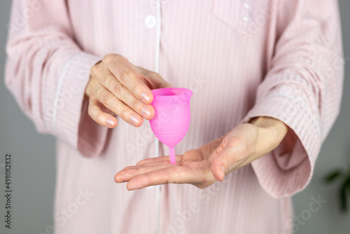 Close-up of a woman's hands holding a silicone menstrual cup. Alternative ecological feminine hygiene product during menstruation waste-free concept