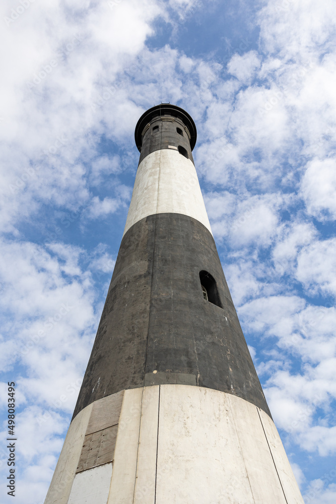 Tall stone lighthouse under a beautiful blue sky with puffy clouds. Fire Island, Long Island New York