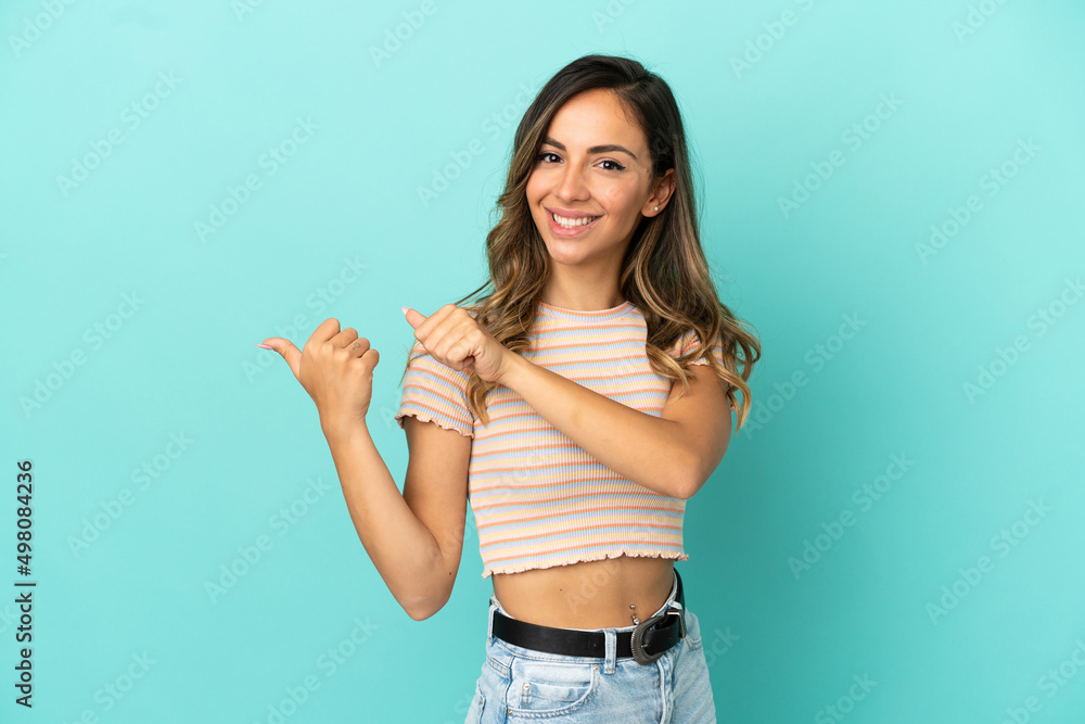 Young woman over isolated blue background pointing to the side to present a product Young woman over isolated blue background pointing to the side to present a product