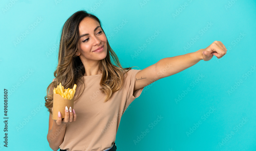 Fototapeta premium Young woman holding fried chips over isolated background giving a thumbs up gesture