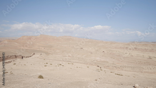 Sandy desert on blue cloudy background. Action. Natural landscape with the endless desert.