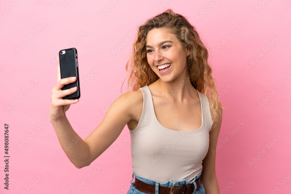 Young blonde woman isolated on pink background making a selfie with mobile phone Young blonde woman isolated on pink background making a selfie with mobile phone