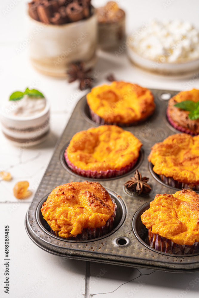 Fototapeta premium Sweet homemade cottage cheese muffins with pumpkin on white background