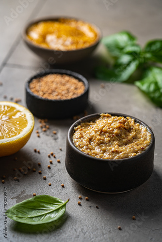 Fresh homemade organic dijon mustard in a bowl on gray background, close up