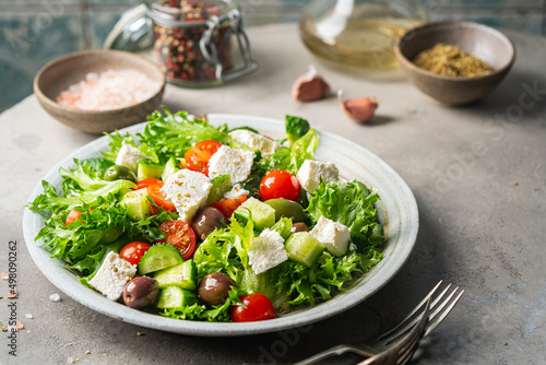 Classic vegetable salad with fresh olives  tomatoes  cucumbers  greek cheese feta and olive oil on gray background.