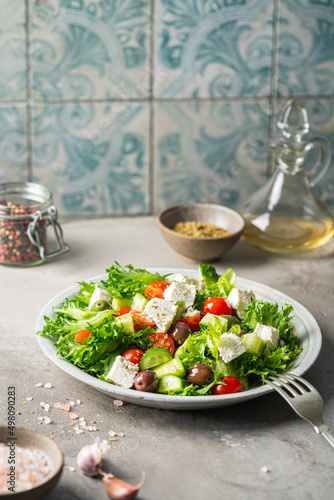 Classic vegetable salad with fresh olives, tomatoes, cucumbers, greek cheese feta and olive oil on gray background.