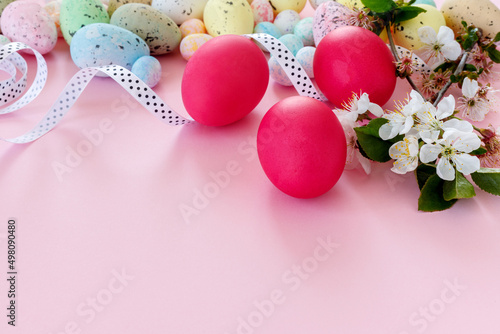 Beautiful Easter card with colorful eggs and cherry branches on paper pink background.