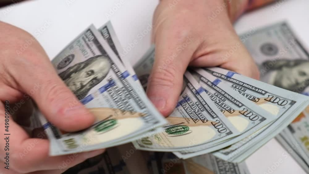 the man counts cash hundred-dollar bills of the USA and puts them in stacks. employee's salary. budget allocation of money. close-up of men's hands counting money. finance and investments. the man counts cash hundred-dollar bills of the USA and puts them in stacks. employee's salary. budget allocation of money. close-up of men's hands counting money. finance and investments.