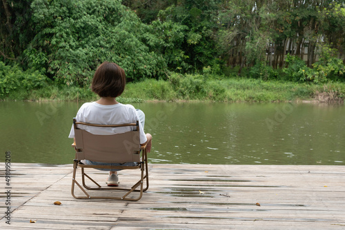 woman sit on arm chair look at the lake nature view.