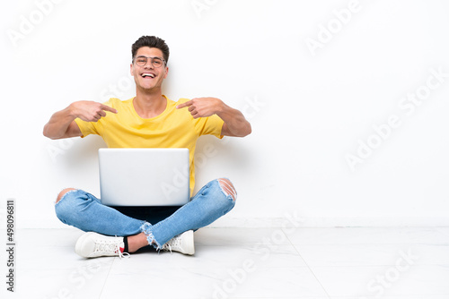 Young man sitting on the floor isolated on white background proud and self-satisfied