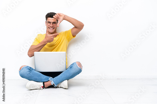 Young man sitting on the floor isolated on white background focusing face. Framing symbol