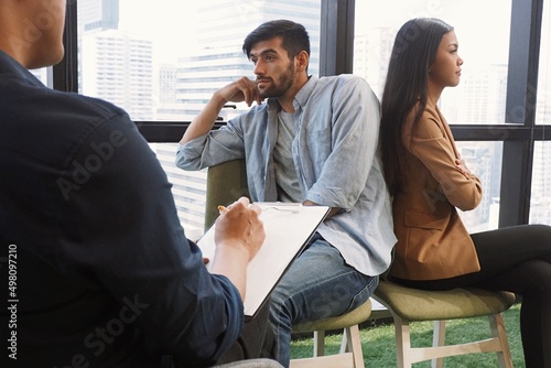 Professional Asian male psychiatrist giving advice to young couple having serious relationship problem and difficulties in living together after marriage Medical mental treatment provided by doctor