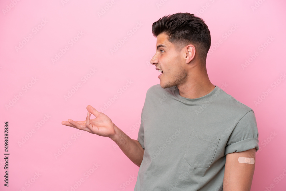 Young caucasian man wearing band-aids isolated on pink background with surprise facial expression Young caucasian man wearing band-aids isolated on pink background with surprise facial expression
