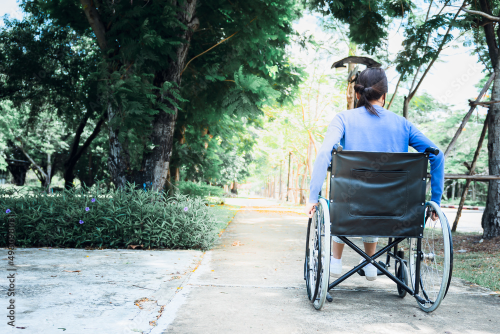 Behind an Asian woman traveling in a wheelchair by herself, to people and health care concept. Behind an Asian woman traveling in a wheelchair by herself, to people and health care concept.