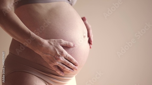 pregnant woman. health pregnancy motherhood procreation concept. close-up belly of a sunlight pregnant woman. woman waiting for a newborn baby. pregnant woman holding her belly indoors