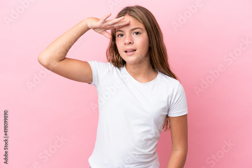 Little caucasian girl isolated on pink background looking far away with hand to look something
