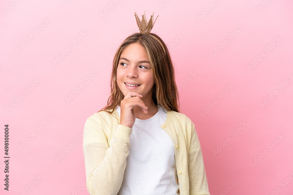 Little princess with crown isolated on pink background looking to the side and smiling Little princess with crown isolated on pink background looking to the side and smiling