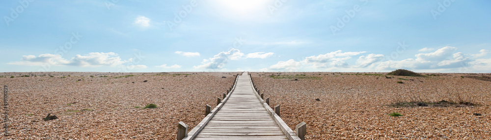 Dungeness Headland is a windswept, desert-like, and forlorn shingle beach. This wooden plank path leads across the stones to the English Channel. Dungeness Headland is a windswept, desert-like, and forlorn shingle beach. This wooden plank path leads across the stones to the English Channel.