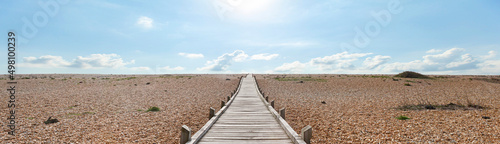 Dungeness Headland is a windswept, desert-like, and forlorn shingle beach. This wooden plank path leads across the stones to the English Channel. photo