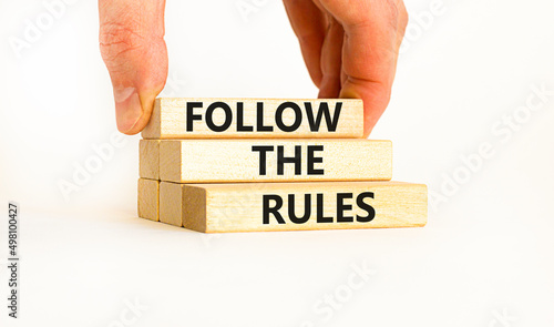 Follow the rules symbol. Concept words Follow the rules on wooden blocks. Businessman hand. Beautiful white table white background. Business and follow the rules concept. Copy space.