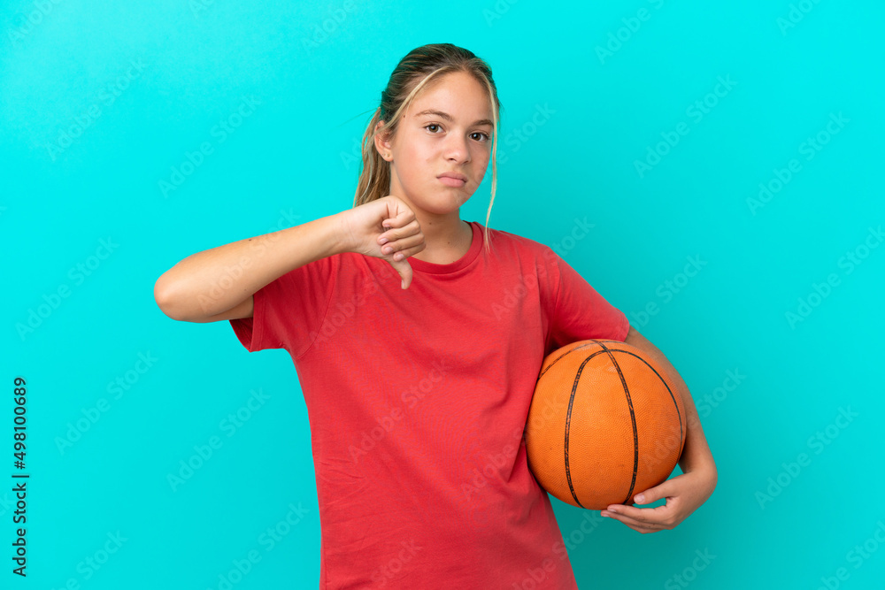 Little caucasian girl playing basketball isolated on blue background showing thumb down with negative expression