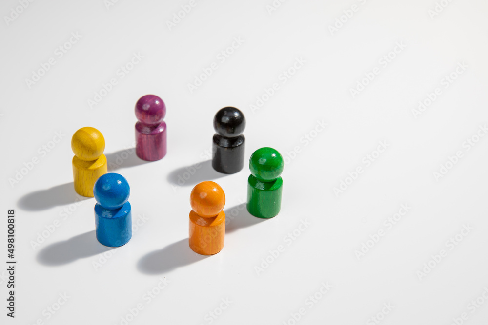 A group of wooden figurines in different colors standing in a circle for the concepts of teamwork, diversity, equality and business A group of wooden figurines in different colors standing in a circle for the concepts of teamwork, diversity, equality and business