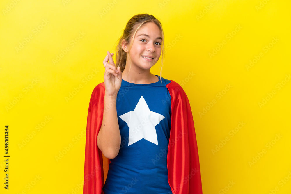 Super Hero little girl isolated on yellow background with fingers crossing and wishing the best Super Hero little girl isolated on yellow background with fingers crossing and wishing the best