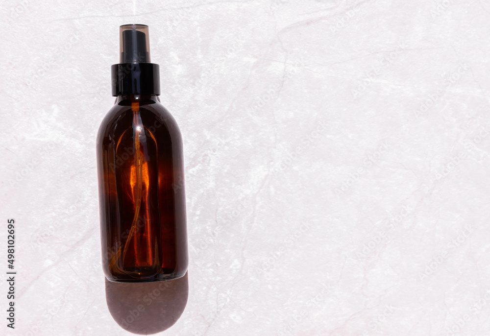 Serum oil essence in a brown glass bottle on a light gray background with a shadow. Skin care cosmetics mockup. View from above. Space for copy. 
