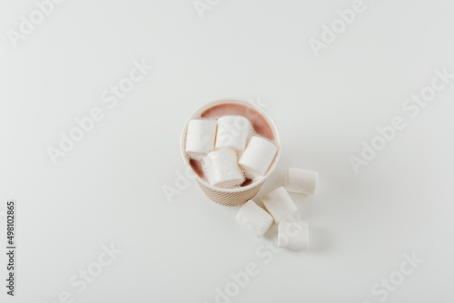 Paper cup with hot drink with marshmallows. White background. Coffee, latte, cappuccino, cocoa. Disposable paper cup. Recycling and eco friendly concept. Top view