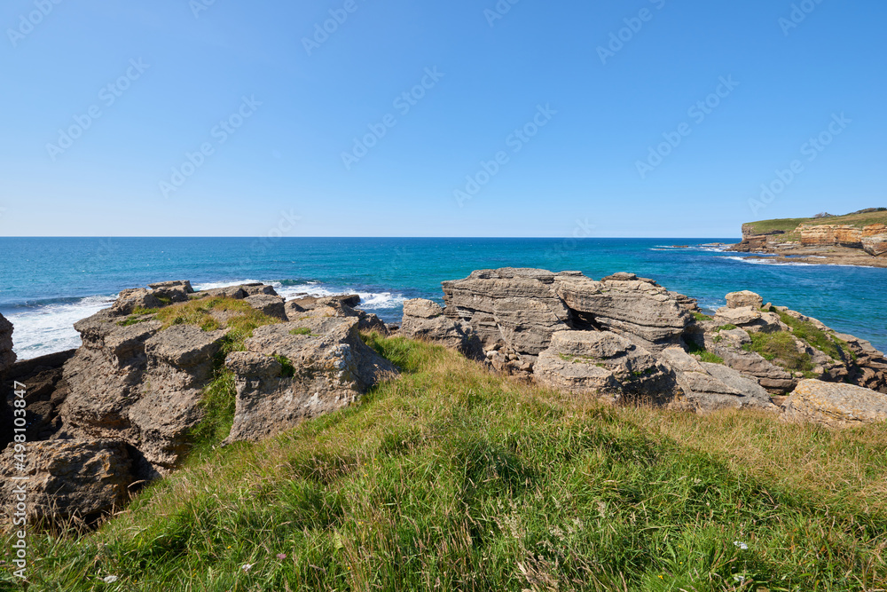 Cliffs surrounded by vegetation under a cloudless sky.