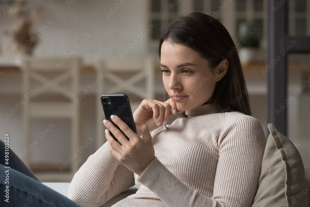 Focused millennial woman using mobile phone at home, reading online content, browsing internet, shopping with application. Gen Z girl texting message on chat on cellphone at home Focused millennial woman using mobile phone at home, reading online content, browsing internet, shopping with application. Gen Z girl texting message on chat on cellphone at home