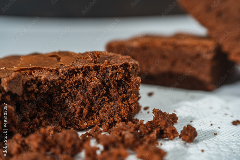 Close up of cubes of chocolate brownies on a white plate on a marble table. Close up of cubes of chocolate brownies on a white plate on a marble table.