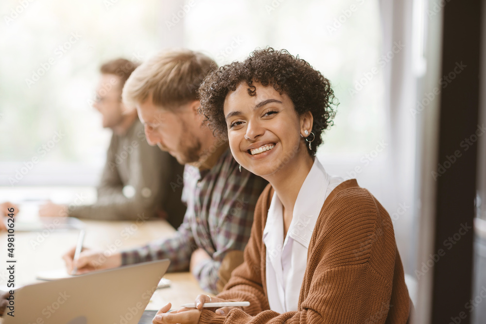 smiling young woman sitting at a table in a coworking center. smiling young woman sitting at a table in a coworking center.