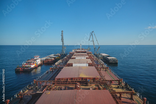Transshipment of grain products at anchorage, barges, floating cranes and bulk carrier photo