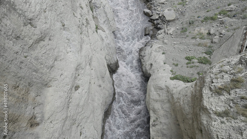 A powerful stream of water is squeezed between the sides of the rocks. Action. Aerial view of the river flowing in a gorge between mountains.