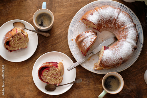 Raspberry roll wreath. Brioche. Top view, wooden background, coffee, powdered sugar, yeast buns. 