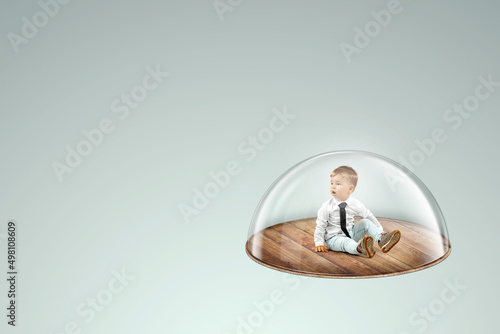 Child safety, overprotection, a little boy sits under a glass dome, cap. Vaccinations, protection against viruses and diseases, maternal love, immunity photo