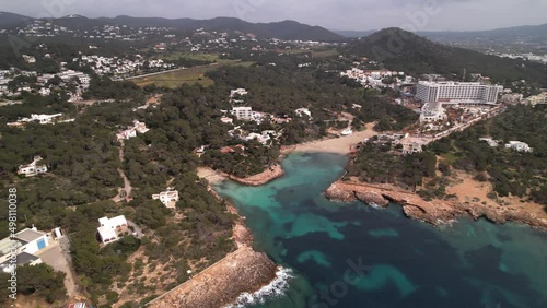 Aerial, Cala Gracio, Ibica, Spain. Breathtaking Balearic island bay with Tourquoise water and green hills covered in clouds photo