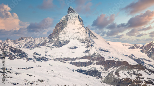 Iconic view of snowy Matterhorn peak with blue sky and clouds, Zermatt, Switzerland