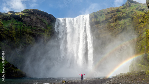 Skogafoss waterfall with an unidentified woman under the waterfall and a rainbow photo