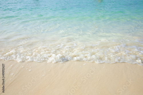 Soft ocean waves on the sandy beach, blue water.