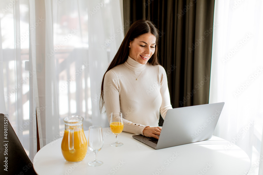Young woman using a laptop computer and drinking healthy orange juice Young woman using a laptop computer and drinking healthy orange juice