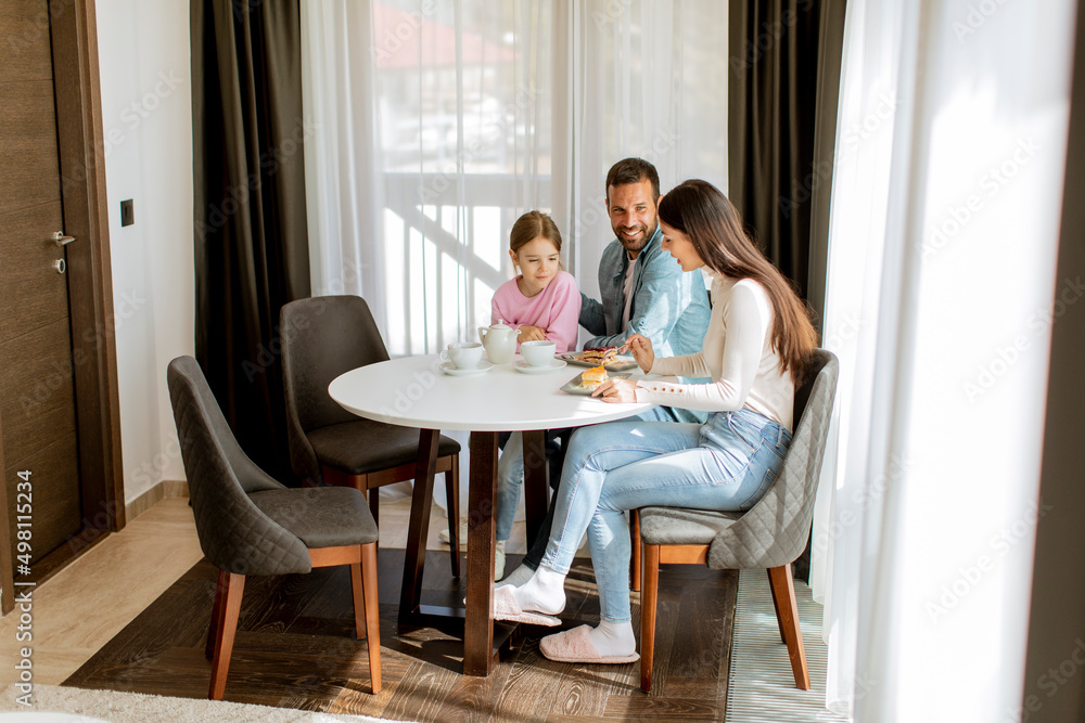 Happy young famila eat cakes and drink tea together Happy young famila eat cakes and drink tea together